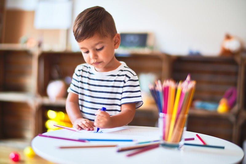 preschool boy drawing with pencils