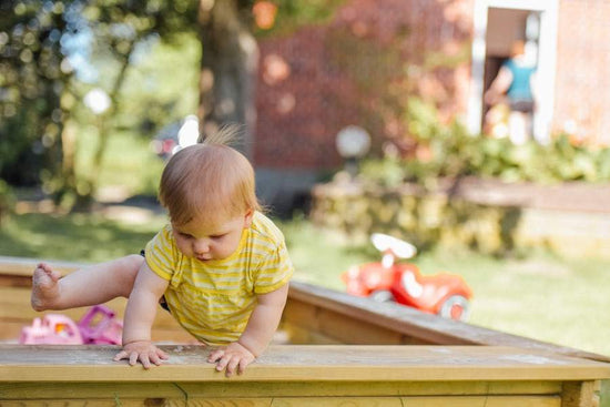 toddler climbing out of sandpit
